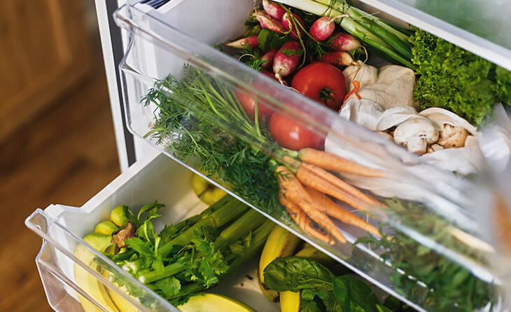 Gavetas da geladeira com verduras e legumes organizados em dois níveis.