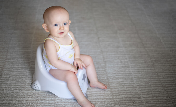 Bebê sentado no pinico de plástico branco e cinza.
