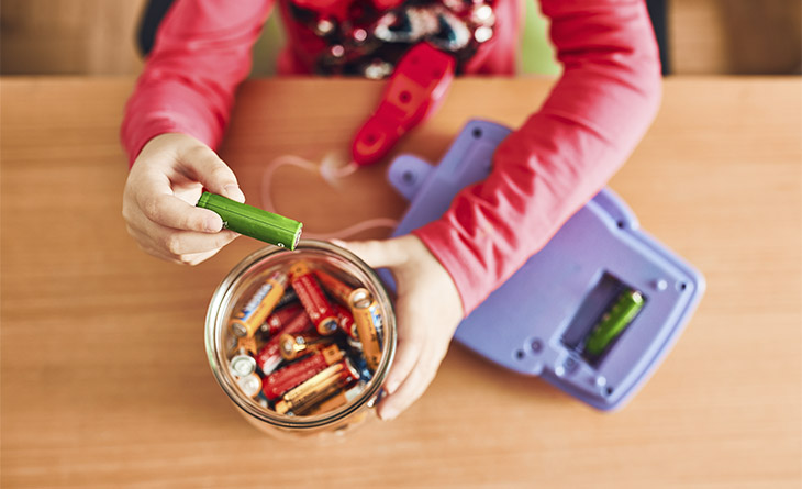 Criança descartando uma pilha no pote de vidro.