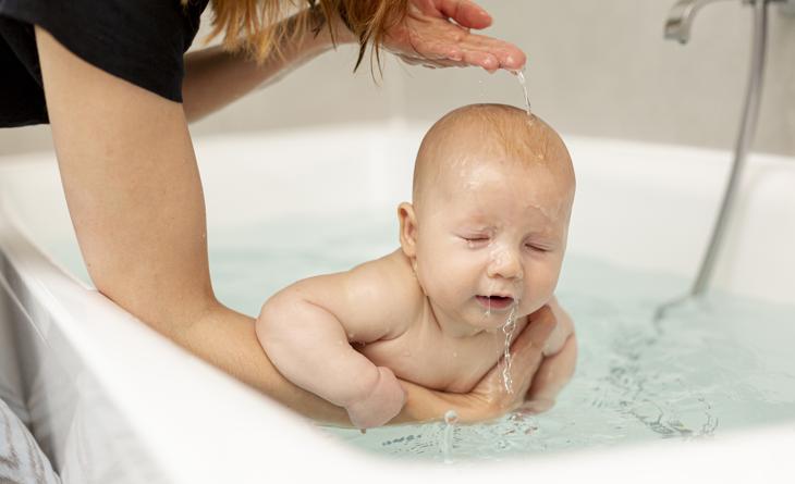 Bebê tomando banho na banheira.