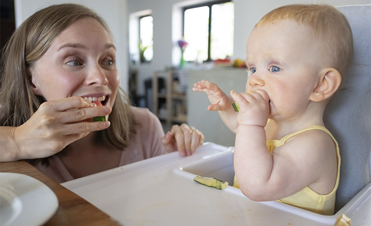 Mãe comendo com o bebê na introdução alimentar.