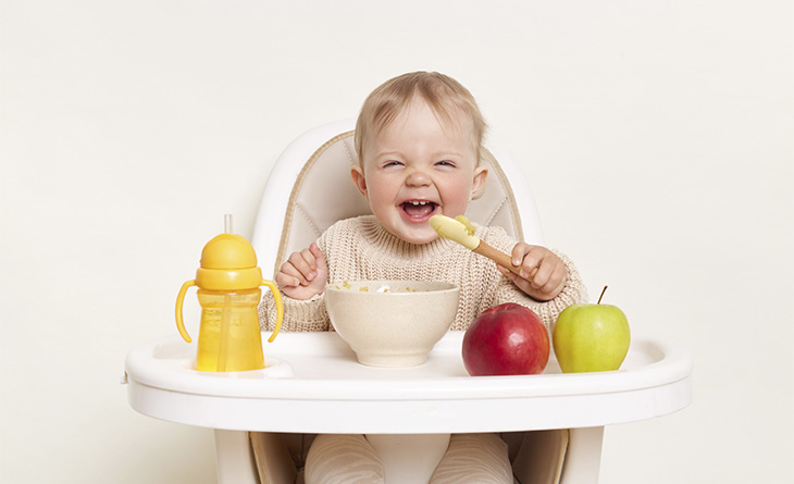 Bebê comendo frutas na tigela.