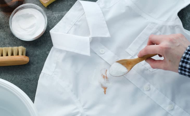 Colher com bicarbonato sobre camisa branca manchada.