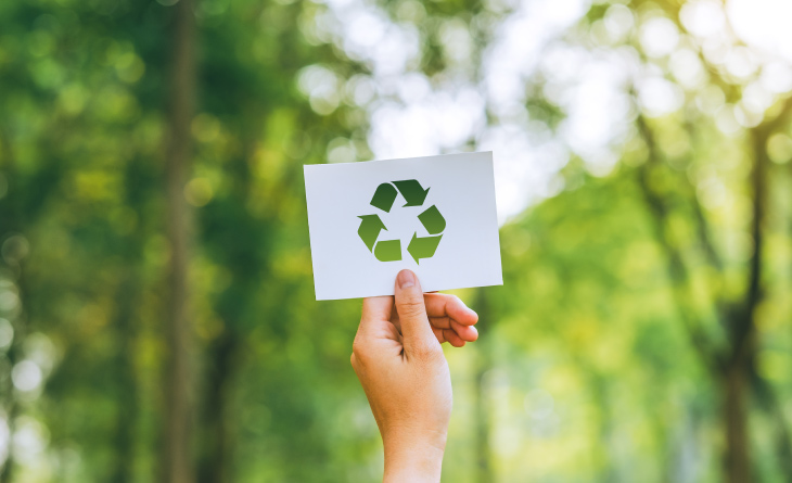 Mão segurando um papel com o símbolo de sustentabilidade.