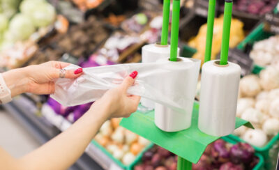 Mulher com as unhas vermelhas destacando um saco plástico no mercado.