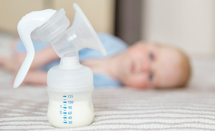 Bomba de tirar leite ao lado do bebê na cama.