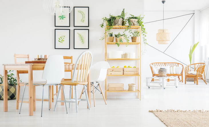 Sala de jantar com mesa e estante de madeira com vasos de plantas e quadros.