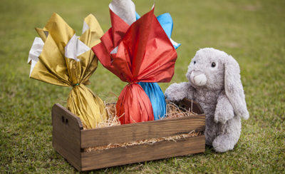 cesto de madeira com três ovos de páscoa dentro.