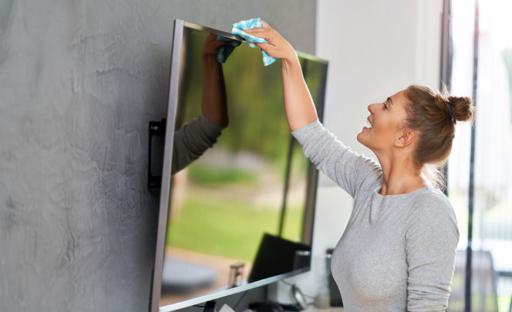 Mulher limpando tela de TV.