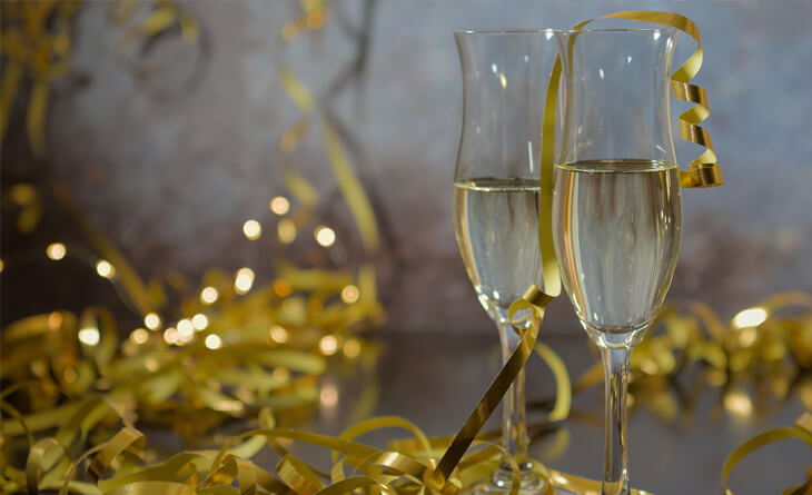 Duas taças com champanhe e a decoração da festa de ano novo em cima da mesa.