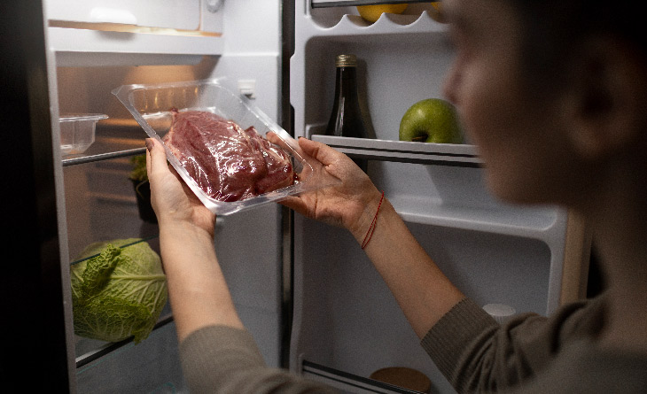 mulher retirando carne da geladeira demonstrando como congelar comida