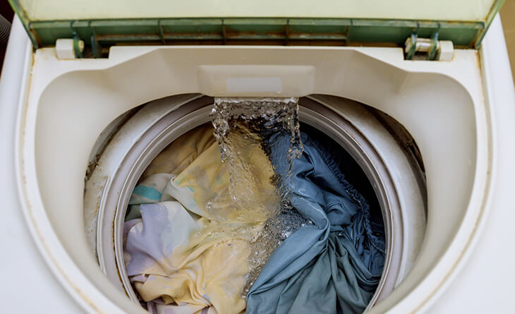 Máquina de lavar com peças amarelas e jeans.