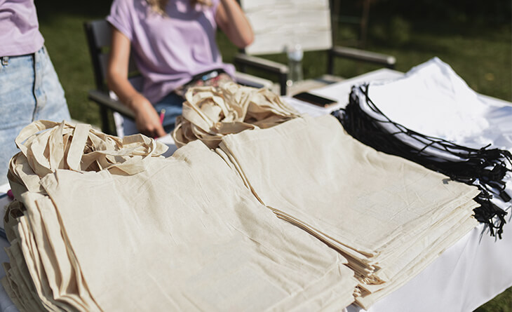 Sacolas com tecido ecológico sendo expostas em feira de artesanato.