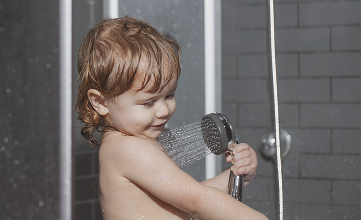 Criança tomando banho com o chuveirinho.