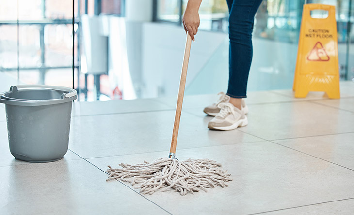 Mulher limpando o chão com esfregão. 