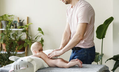 Pai fazendo massagem nas costas do bebê.