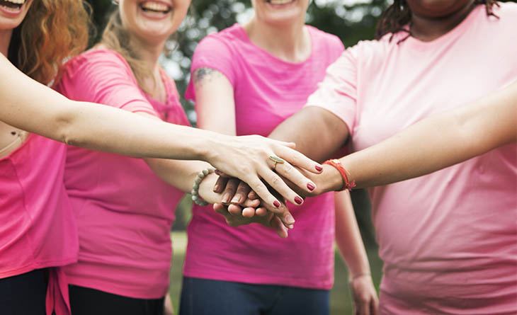 Mulheres de rosa com as mãos juntas