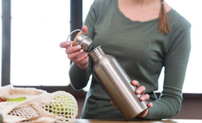 mulher segurando garrada de inox representando como lavar garrafa de água
