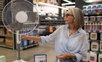 Mulher ligando ventilador em loja.