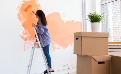 Mulher pintando a parede da sala de laranja.