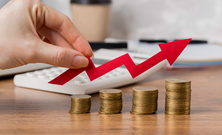 Pessoa segurando uma seta que indica crescimento numa pilha de moedas.