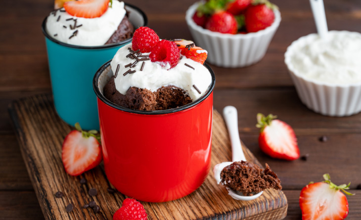 Bolo de caneca com cobertura de chantilly e morango.