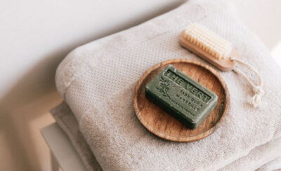 Toalha de banho em cor clara com sabonete e esponja em cima.