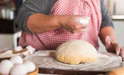 Pessoa colocando farinha sobre massa de pão.
