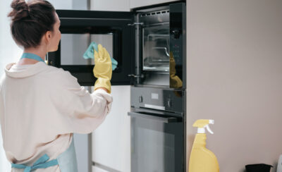 mulher de luva e pano na mão mostrando como limpar forno elétrico