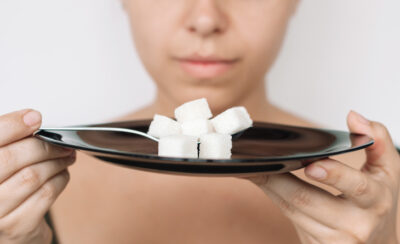mulher segurando prato de açúcar para representar como reduzir o consumo de açúcar