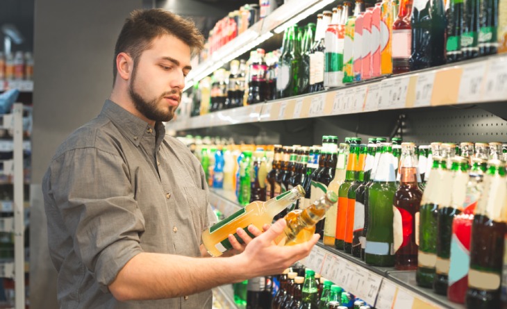 Homem escolhendo bebidas no mercado.