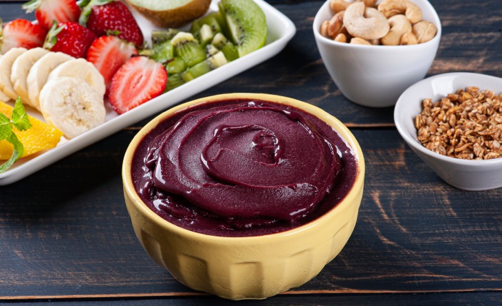 Pote de açaí ao lado de bandeja com frutas fatiadas.