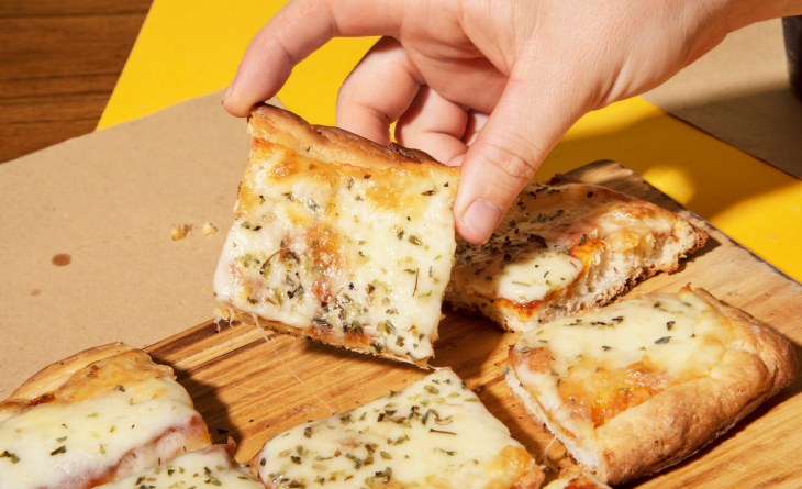 Mão segurando pedaço de pão caseiro.