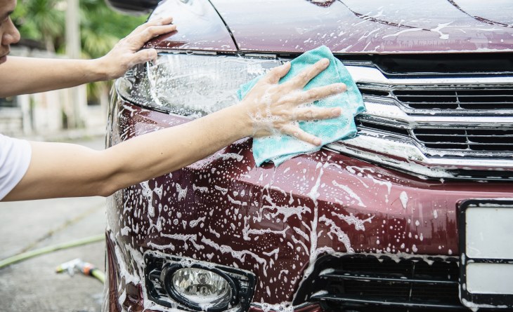 Homem lavando carro na rua.