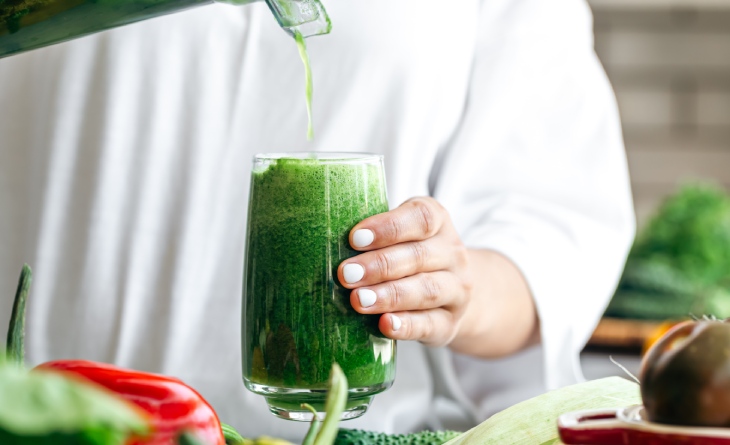 Suco verde sendo despejado no copo.