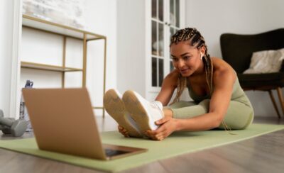 Mulher alongando enquanto olha para o computador em sua frente.