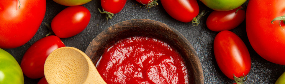 Pote com extrato e tomates ao redor.