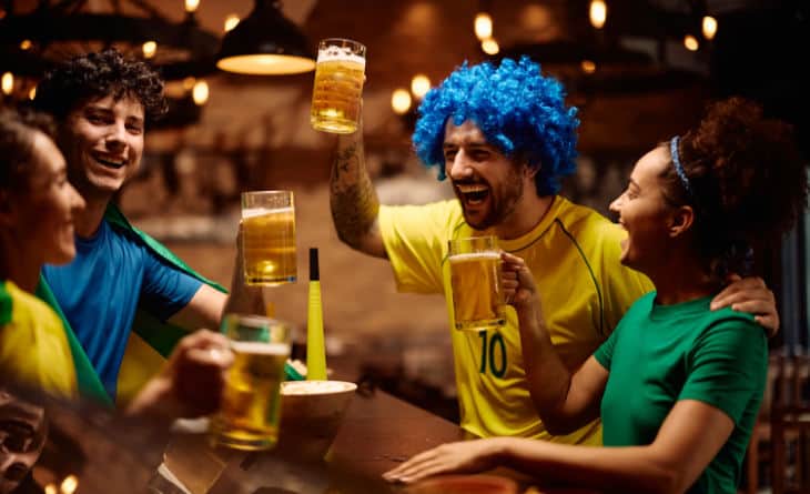 Grupo de pessoas brindando com copos de cerveja.