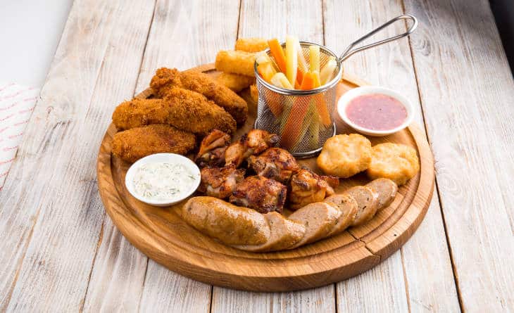 Tábua com petiscos, como batata frita, frango, nugget e linguiça.