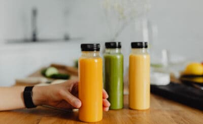Três garrafas de suco sobre bancada da cozinha.