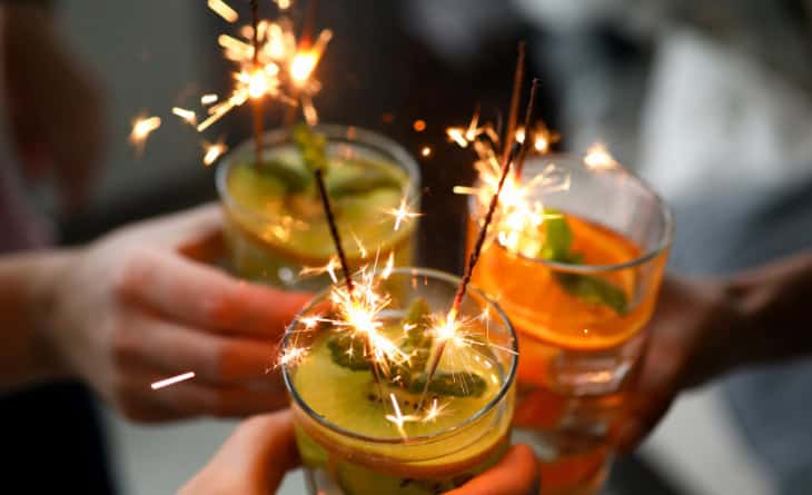 Brinde com três drinks com velas acesas.