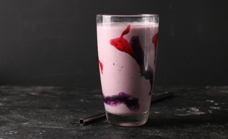 Copo de vidro com batida de vinho e calda nas laterais.