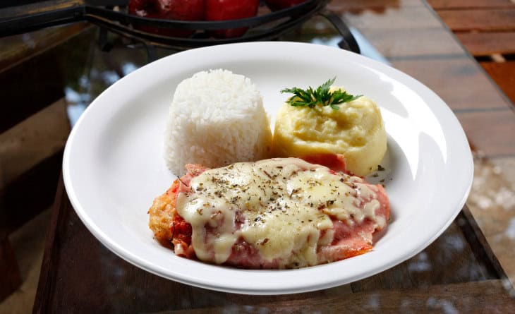 Prato com arroz, purê e bife à parmegiana.