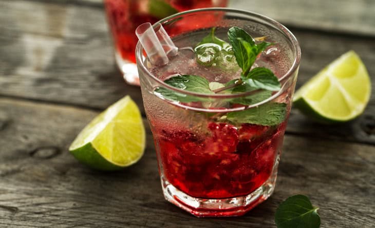 Copo de vidro com caipirinha de vinho, ao lado de pedaço de limão.